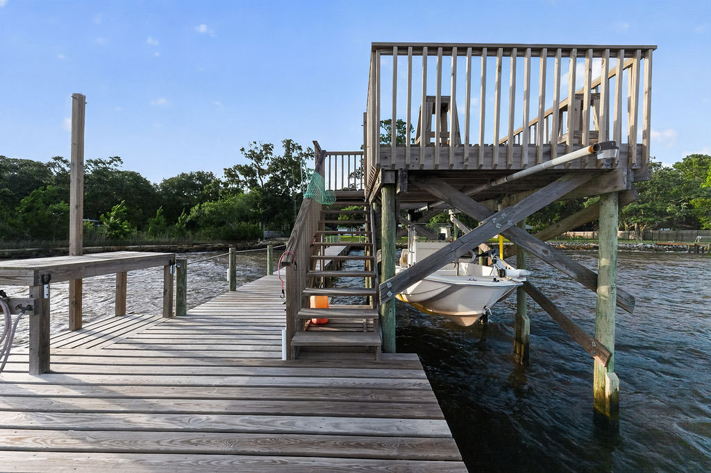 Dock detail showing the boat lift with a boat raised over the water and stairs up to the sundeck