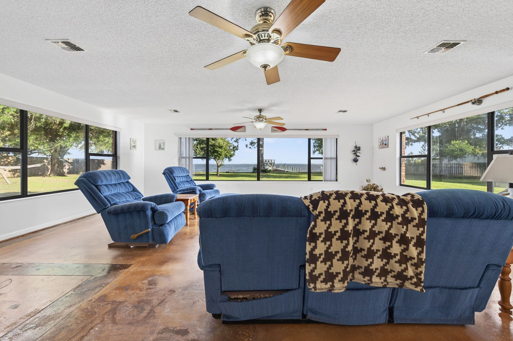Family room interior with windows on three sides looking out over the lawn to the bay