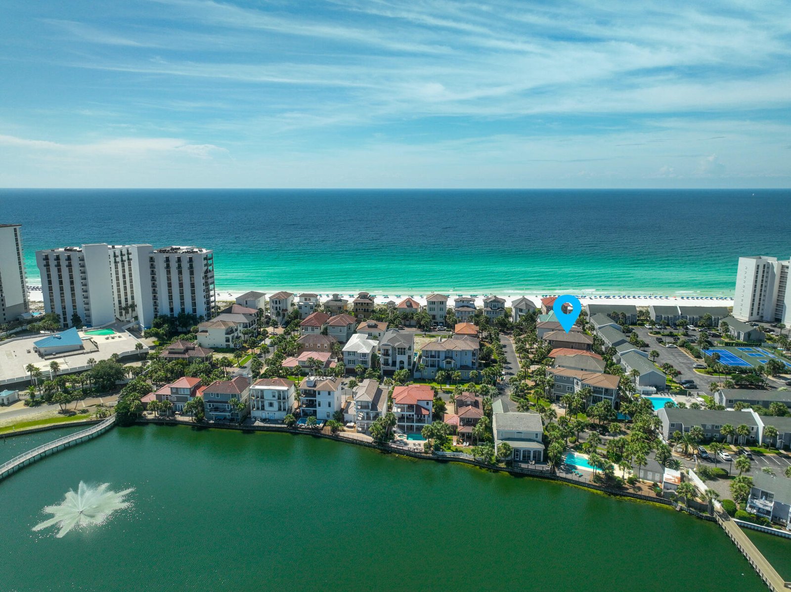 Drone photograph of a Gulf-front neighborhood with the subject home marked by a pin