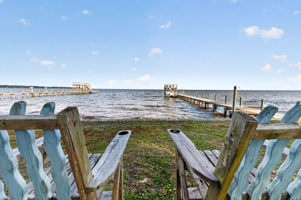 Adirondack chairs at the shoreline looking out over the dock and open water